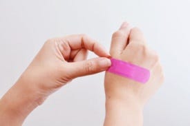 Child putting on pink bandaid