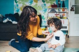 Woman holding breathing mask to childs mouth